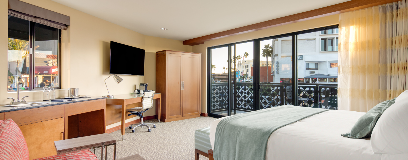 A room in the new Cormorant Hotel in La Jolla. There are yellow walls, built-in furniture and a blue bed skirt.