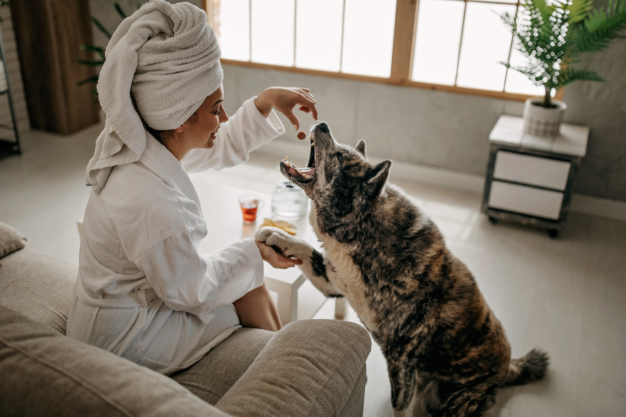 Women in robe feeding her dog. 