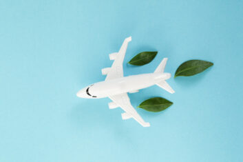 White airplane model emitting fresh green leaves on blue background