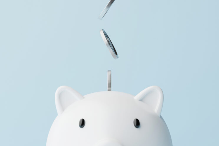 coins falling from above into white piggy bank