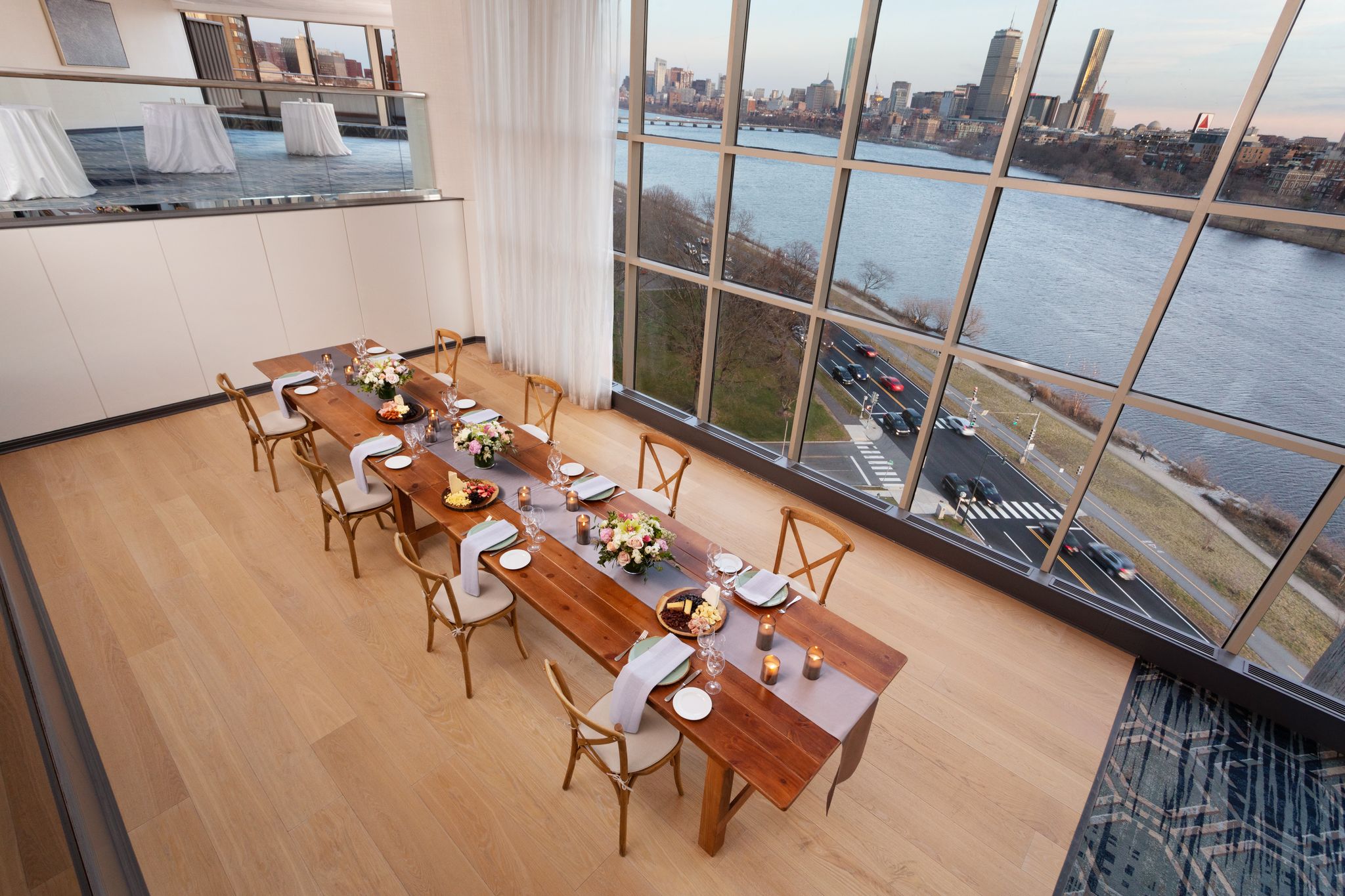 A newly renovated meeting space at Hyatt Regency Boston / Cambridge overlooking the river. A dining table and reception tables are in front of a large window