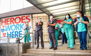 health-care workers standing and clapping in front of hospital