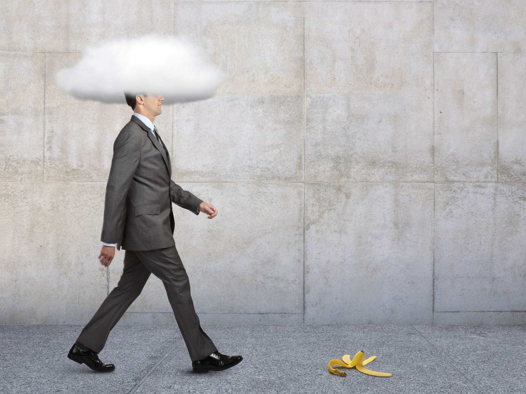 businessman with heads in clouds walking toward banana peel on ground