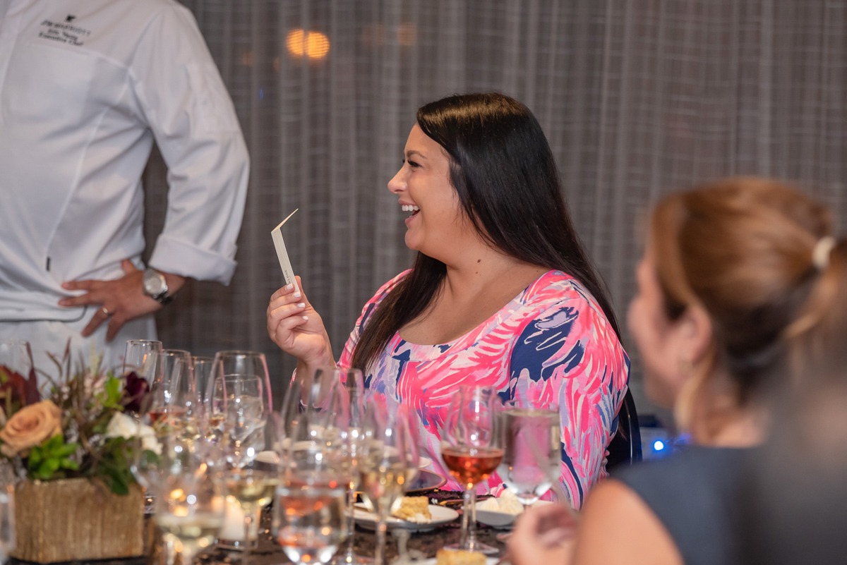 a woman sits at a table with a scent card in her hand