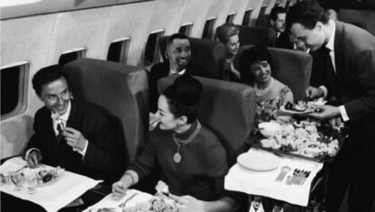 couple is served by airline attendant on airplane