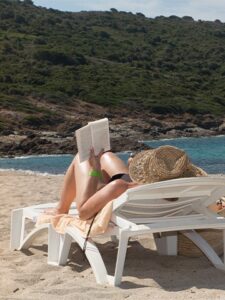 woman reading and laying down at beach