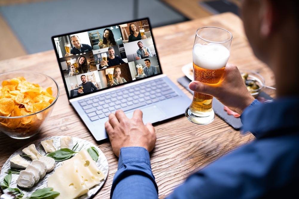man drinking beer and sitting on laptop talking to people
