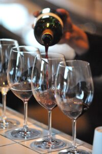 person pouring wine into wine glasses