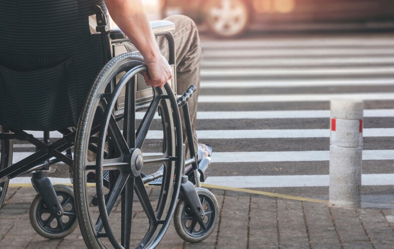 Disabled man in wheelchair preparing to cross road on pedestrian crossing