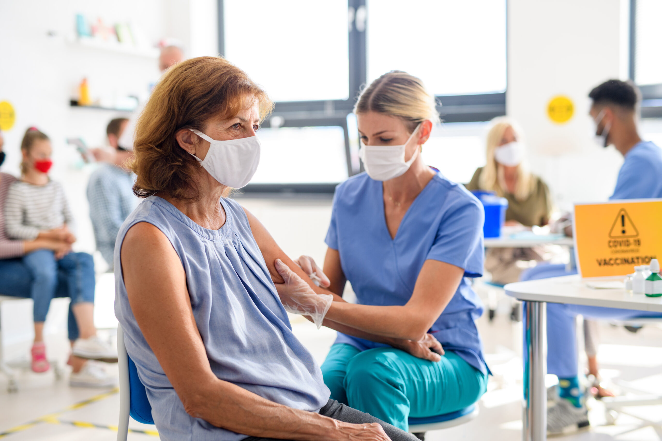 female medical care worker giving woman vaccine 