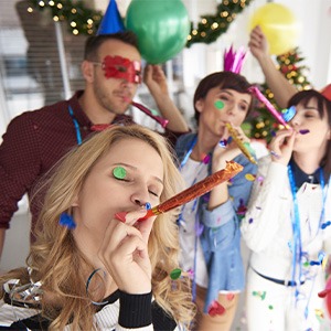 office colleagues wearing party hats of various colors, having party in room with balloons and streamers 