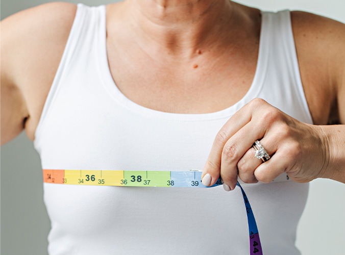woman in shite shirt using ruler tape to take her measurements