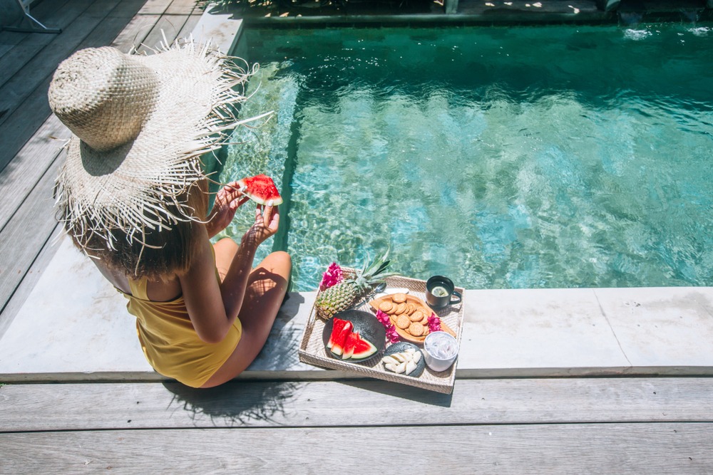 Girl relaxing and eating fruits in the pool on luxury villa in Bali