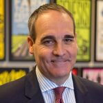 headshot of mike testa wearing black suit, blue and white vertically stripped dress shirt and red tie