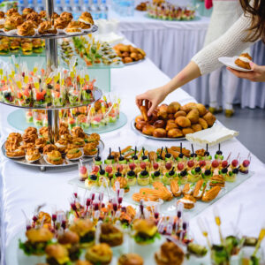 woman selecting a breaded hors d'oeuvre on a table full of various hors d'oeuvres