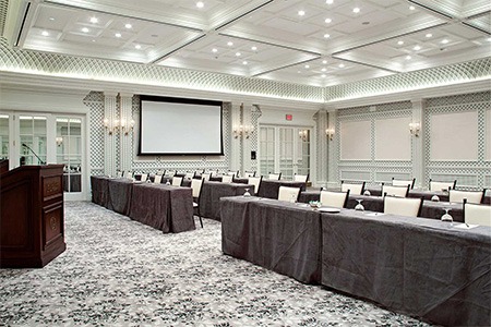 ballroom with light gray carpet floors, tables covered with gray tablecloths and white chairs