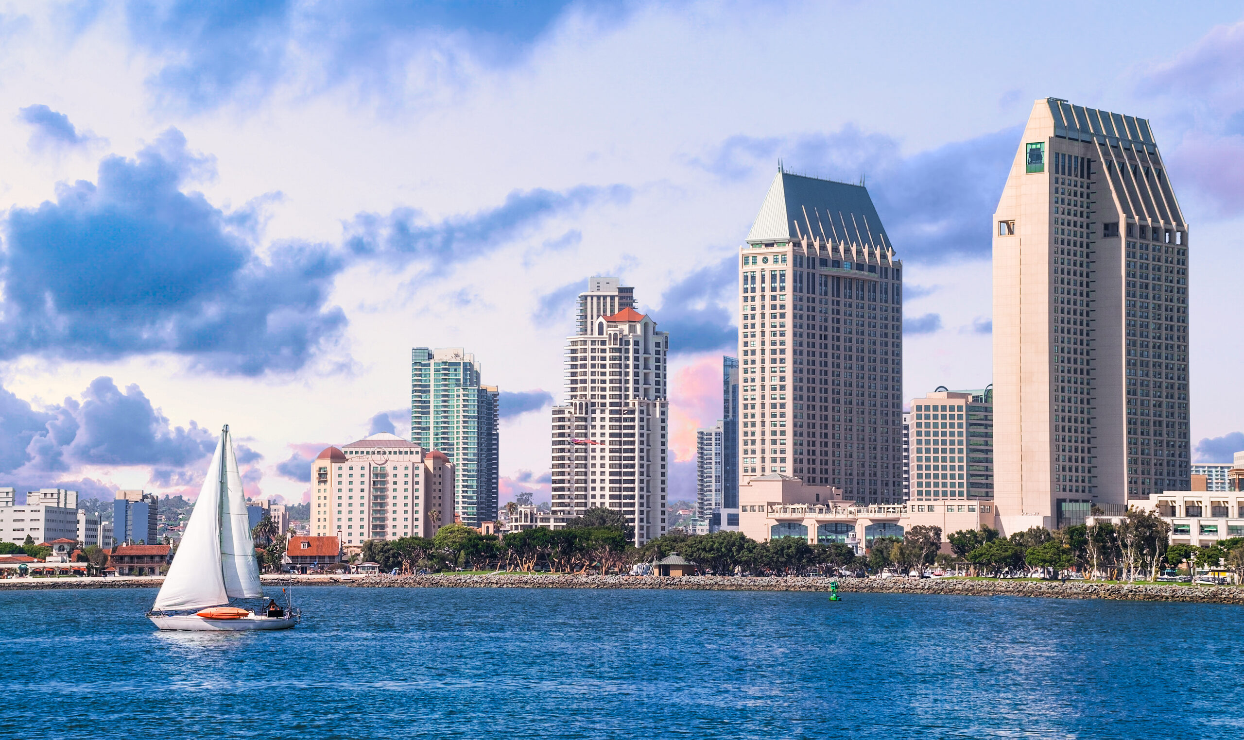 view of San Diego coast from ocean, small boat in water and five buildings in background