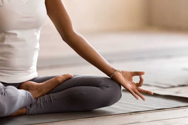 woman sitting and practicing yoga lesson, breathing and meditating