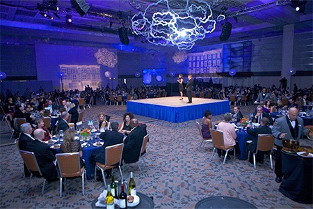 ballroomroom with purple lights in Baltimore Convention Center, two people standing on stage surrounded by people