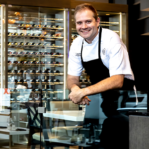 adam middleton wearing white chef jacket and black apron