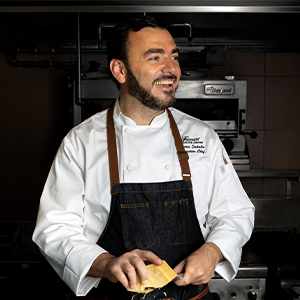 adam middleton wearing long sleeve white chef jacket and black apron