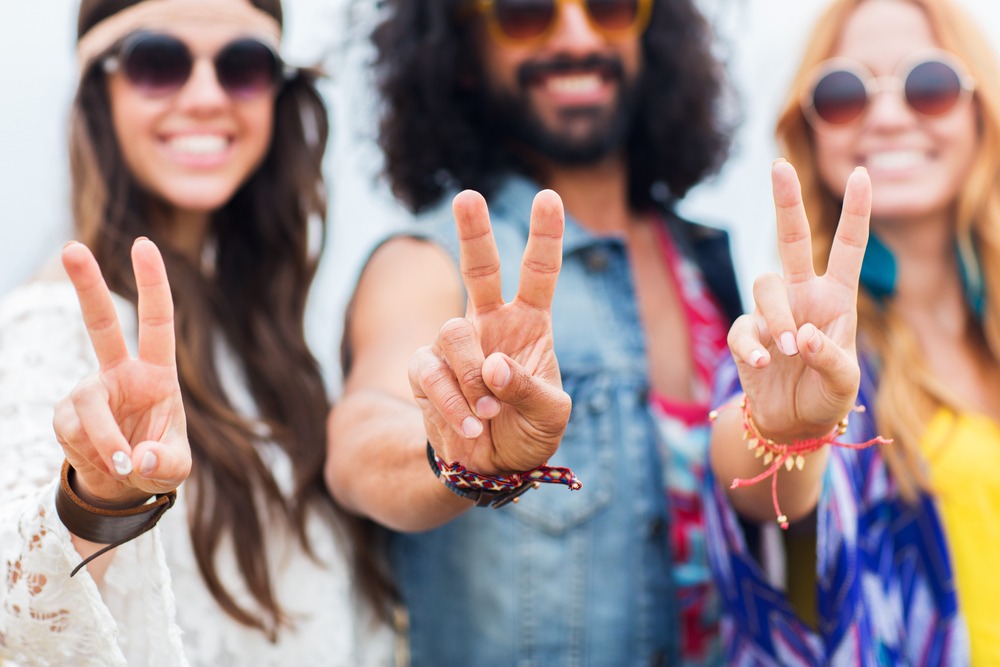 smiling young hippie friends in sunglasses showing peace hand sign