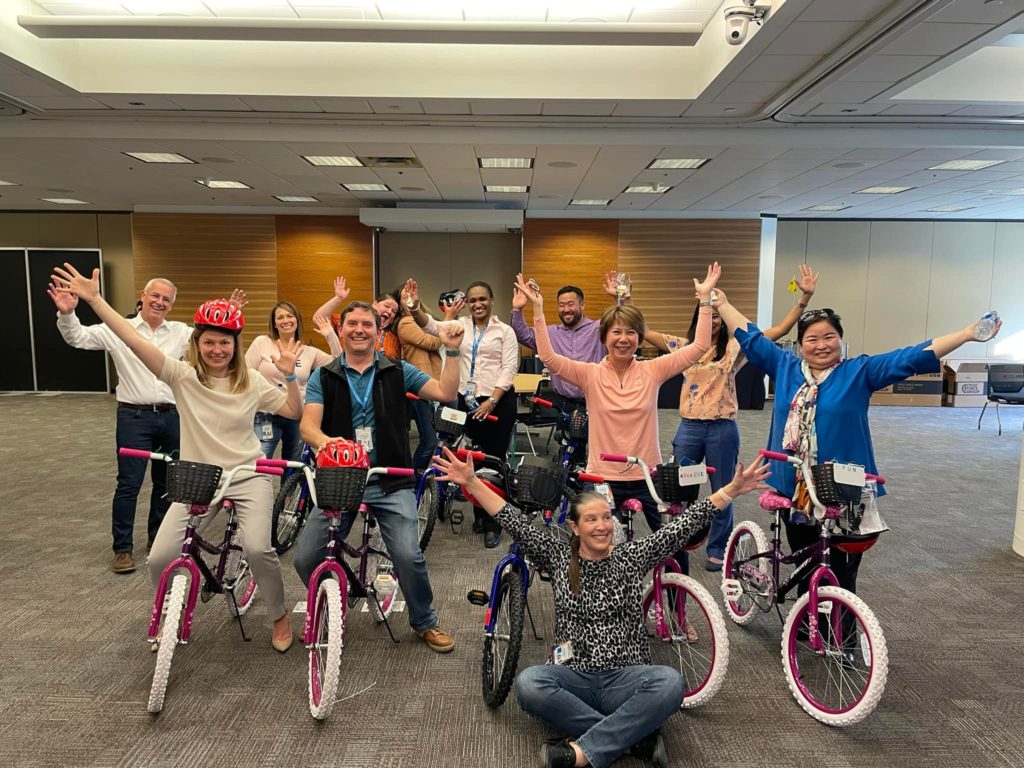 people posing, several kids on pink bikes and adults