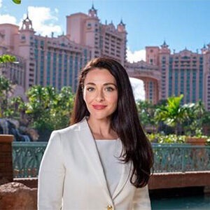 liliana dale standing in front of cityscape, wearing white coat and white shirt