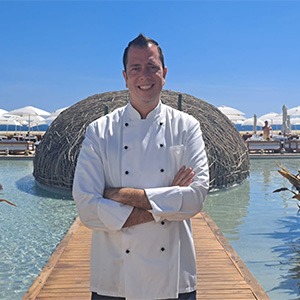 man crossing arms, wearing white chef shirt