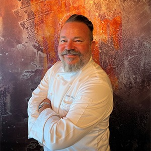 man crossing arms, wearing chef shirt