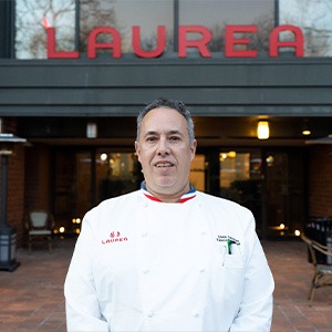 man standing in front of hotel entrance, wearing chef shirt