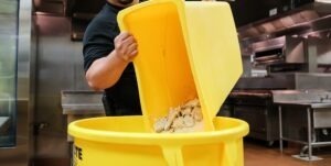 man dumping from in yellow garbage can