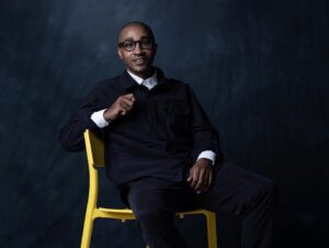 michael tennant, CEO and Founder of Actually Curious, sitting in chair wearing blue button up outerwear and white dress shirt