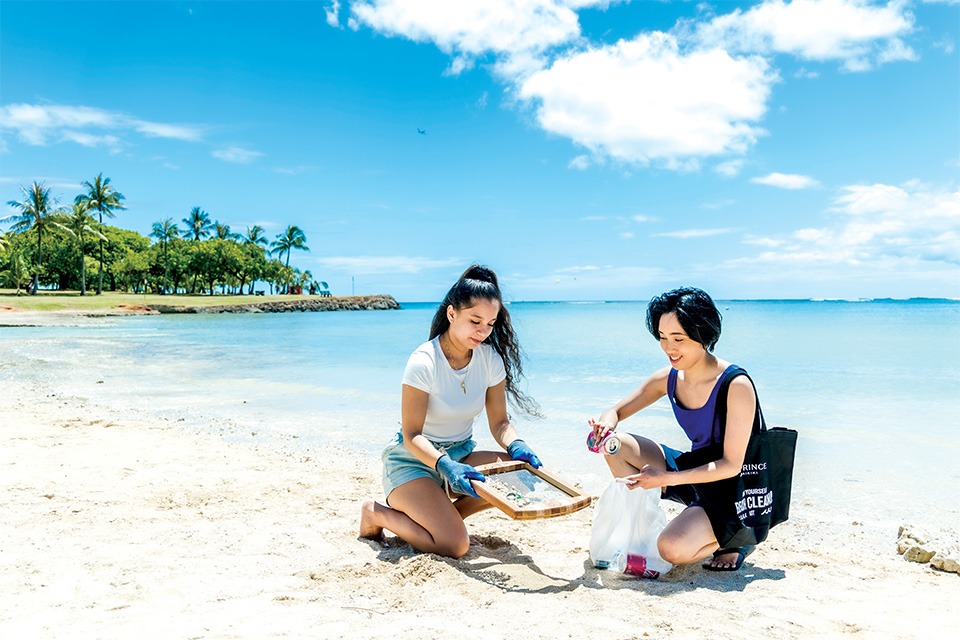 two women cleaning up trash on beach