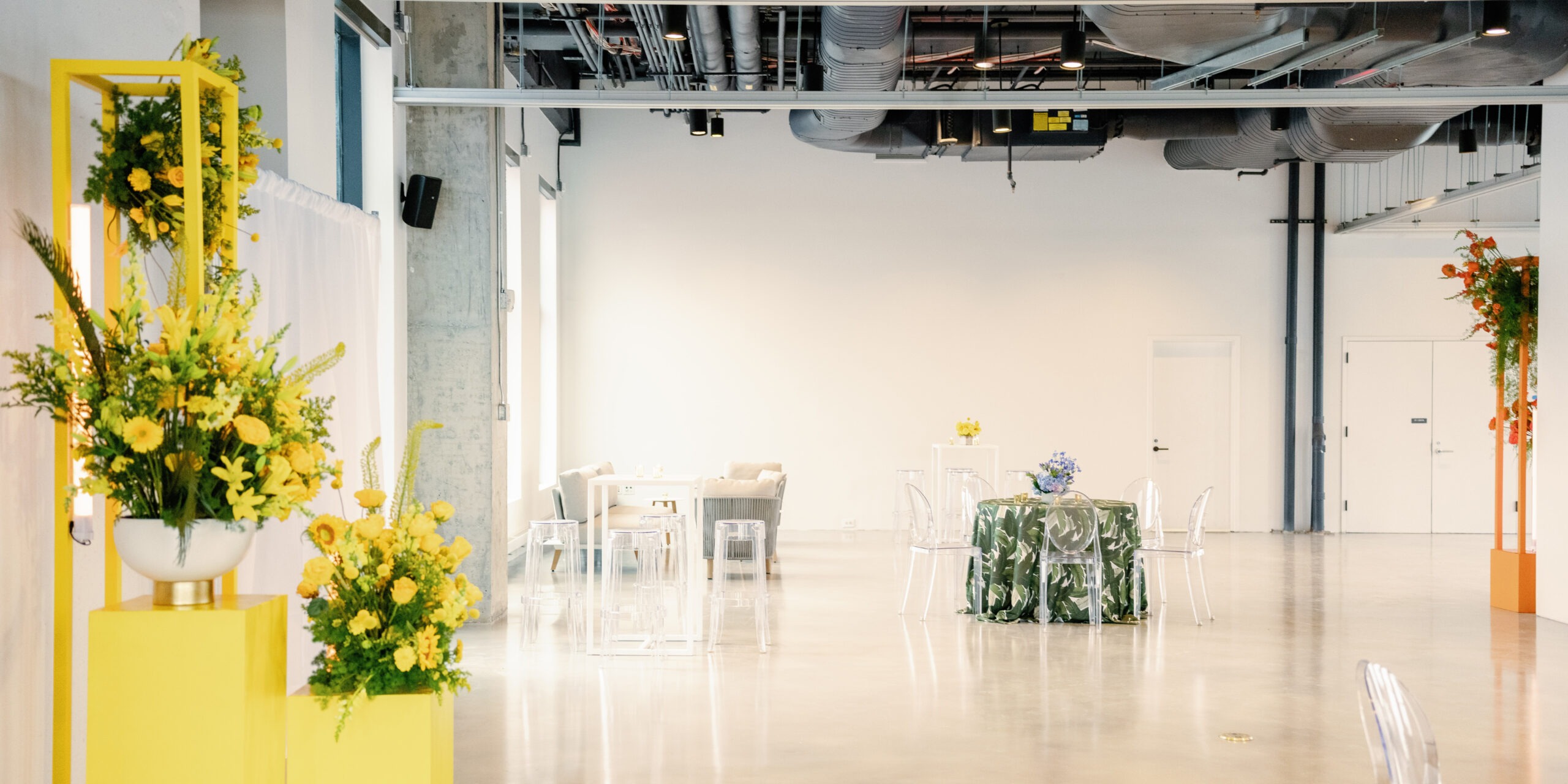 a bright meeting space featuring yellow flowers and exposed industrial roofing
