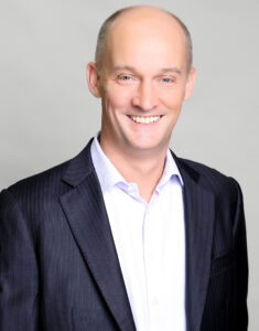 man smiling, wearing black sport coat and white dress shirt