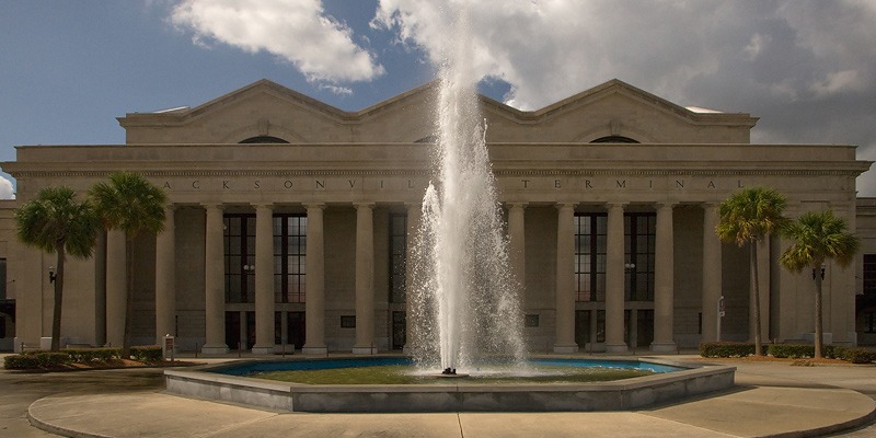 A fountain runs in front of a white building with Greek-style architecture