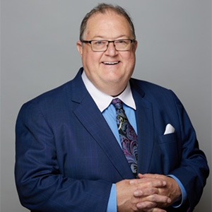 man crossing fingers, wearing blue sport coast and light blue dress shirt with white collar