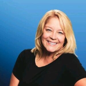 Michele Dobnikar, president of GlobalMeet, smiling in black shirt with blue background looking at camera