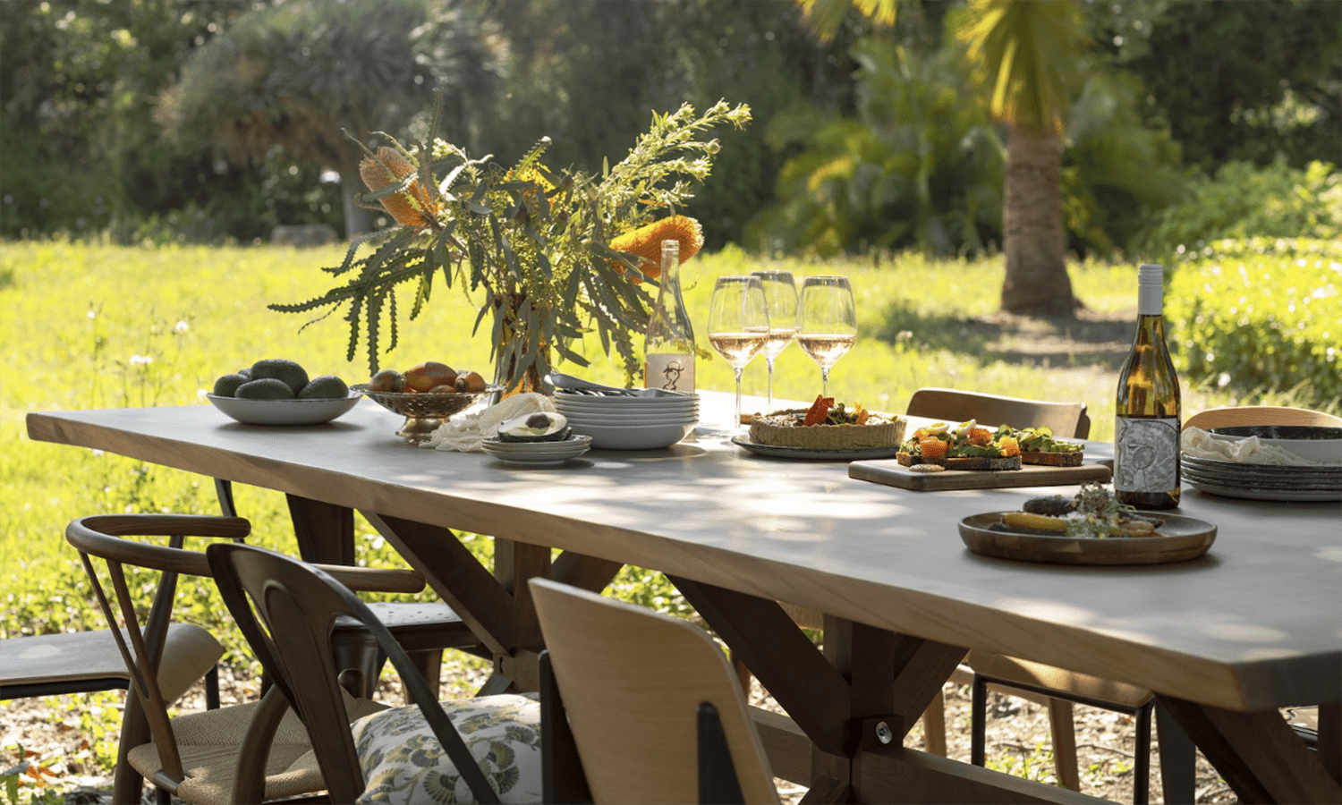 A table set for a summery gathering stands outside in a garden