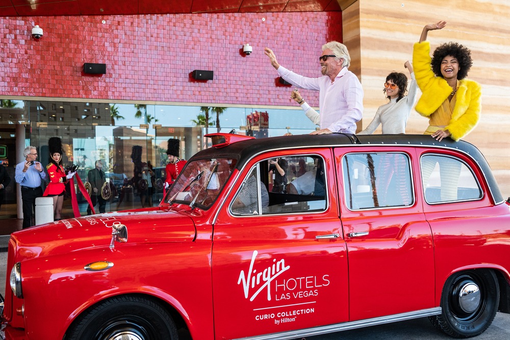 man standing out of sunroof of old school car