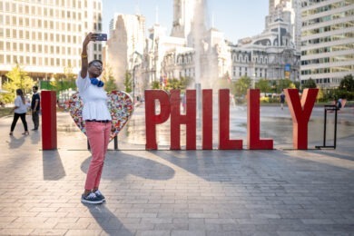 woman taking image of herself in front of "philly" sculpture