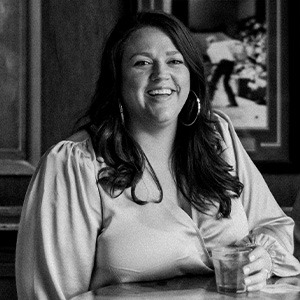 black and white image of woman smiling, wearing silk long sleeve shirt