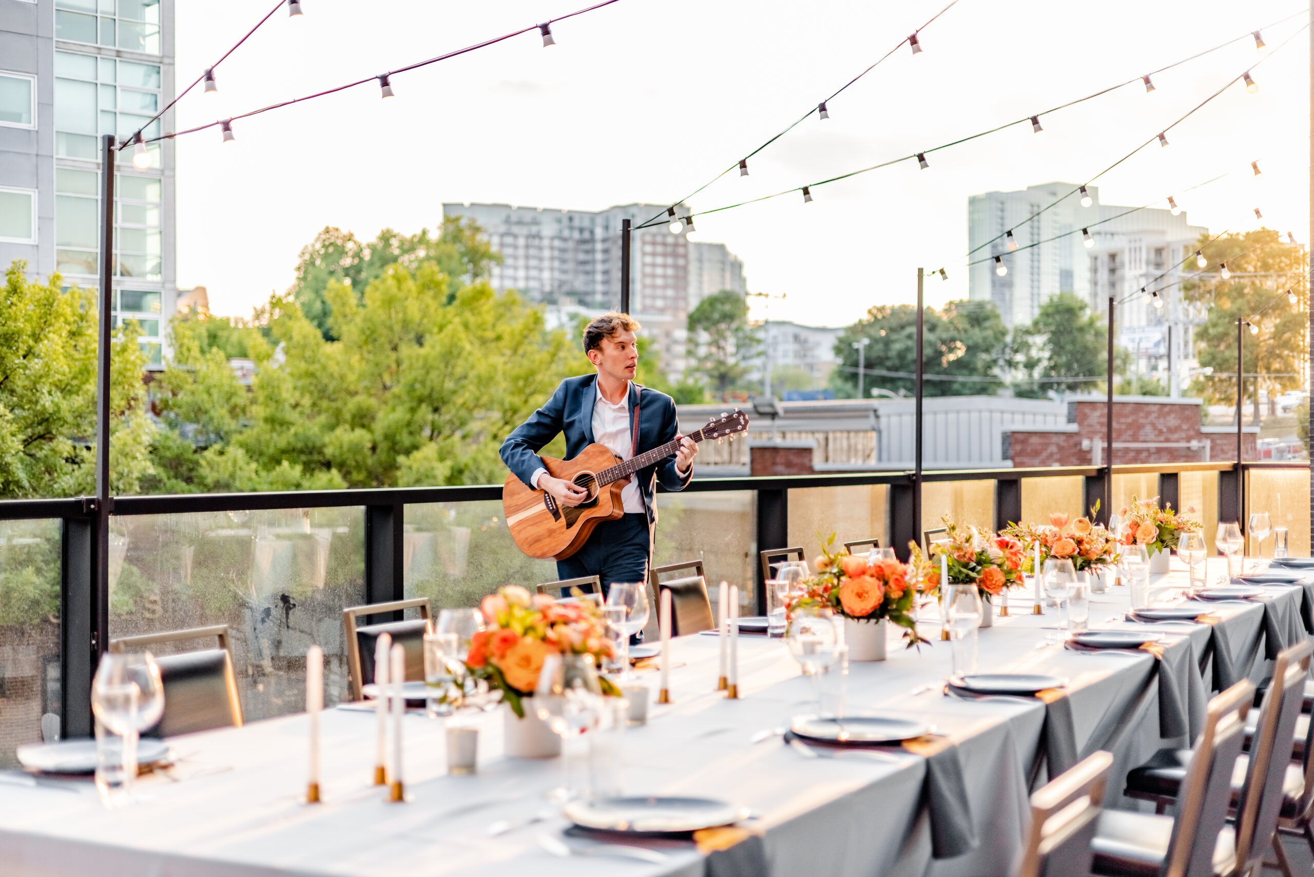 man with guitar in hand singing around table