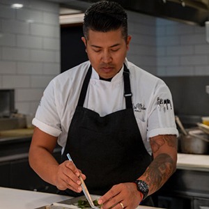 Headshot of Ryan Cruz plating in the kitchen