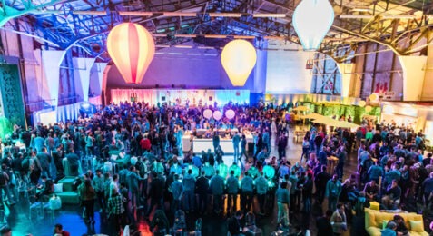 hangar full of people for event with three suspended hot air balloons