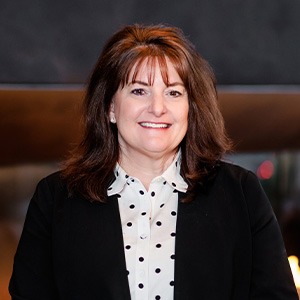 woman smiling, wearing white shirt with black polka dots and black coat