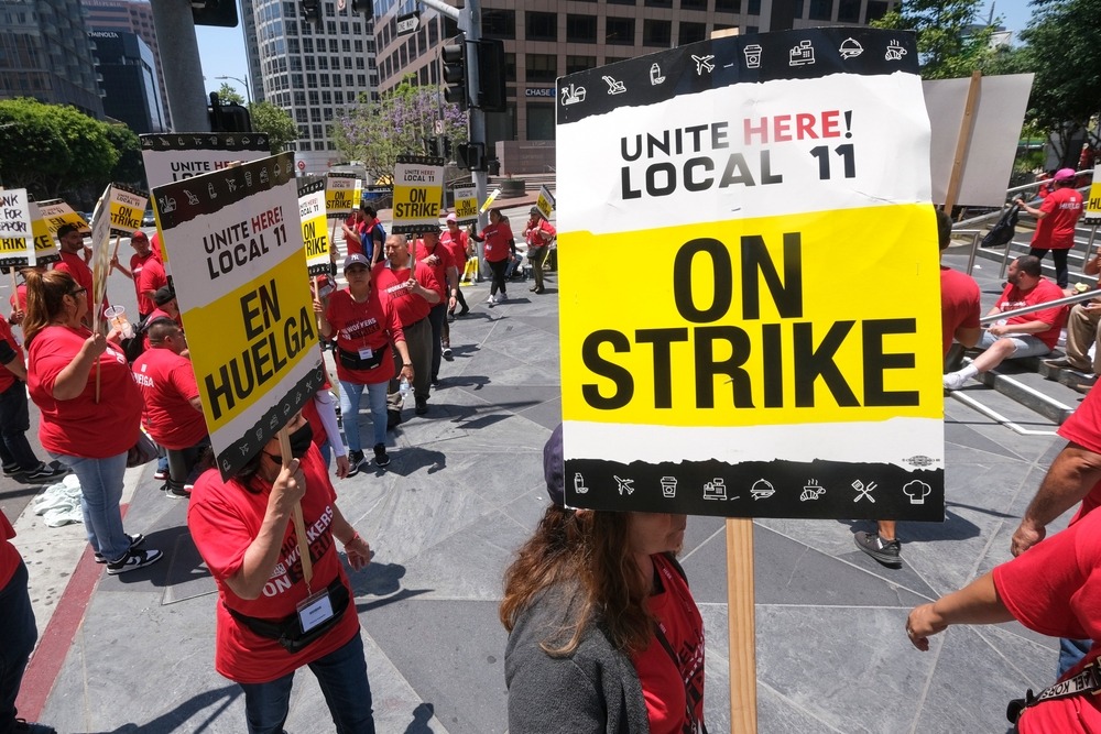 Striking hotel workers holding signs rally outside hotel