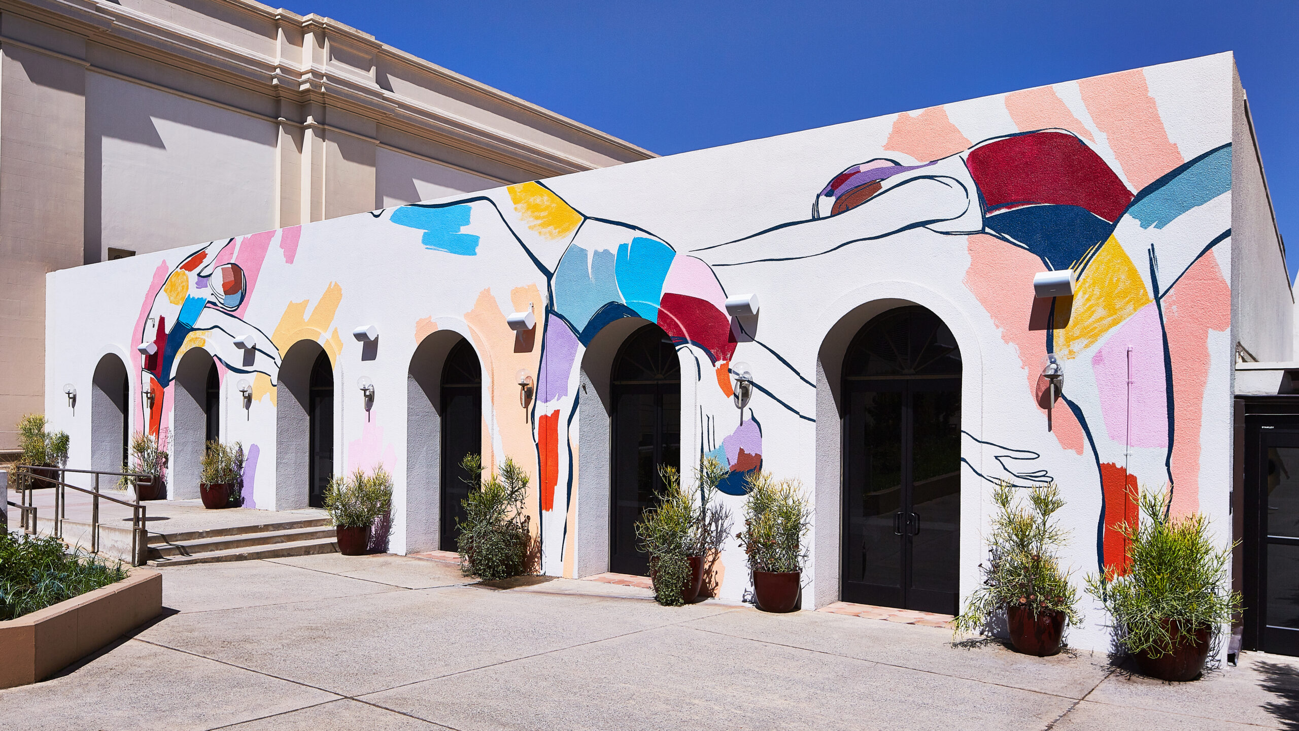 A mural by Leah Tumerman at Hotel Dena featuring colorful silhouettes dancing