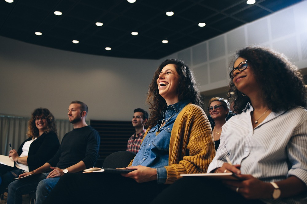 Businesswoman sitting in the audience and laughing during a corporate event